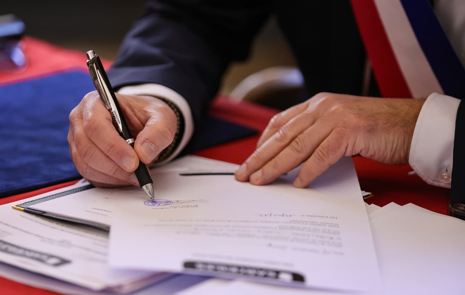 A hand signing a printed letter with a pen