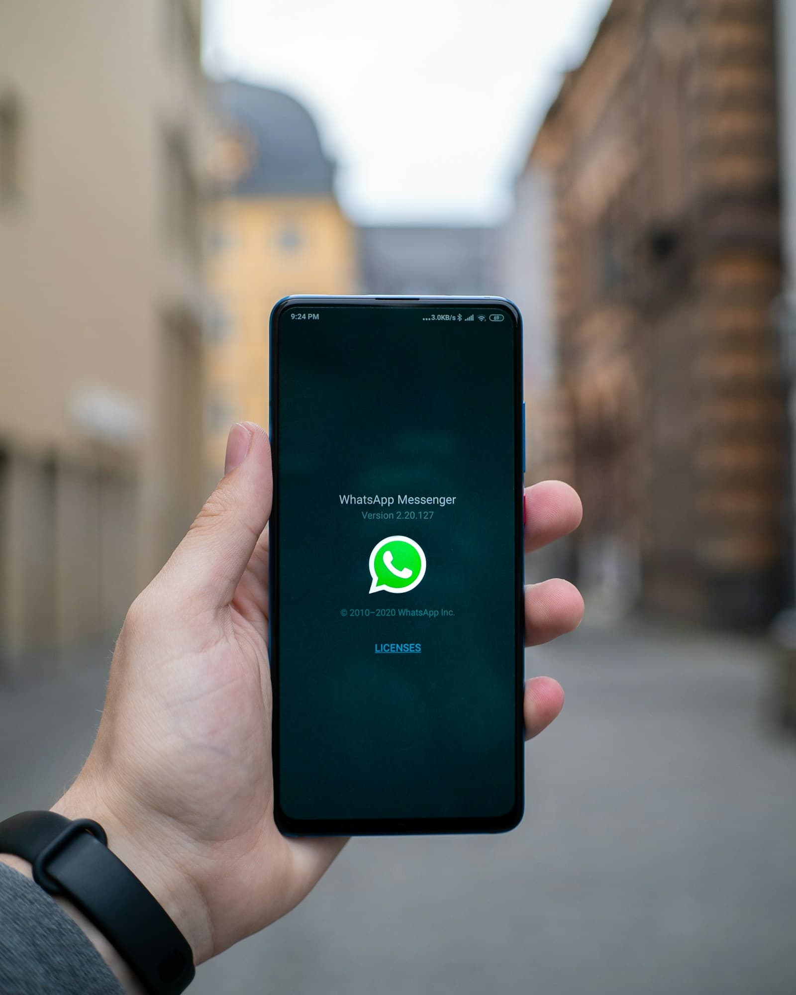 A hand holding a phone opening WhatsApp